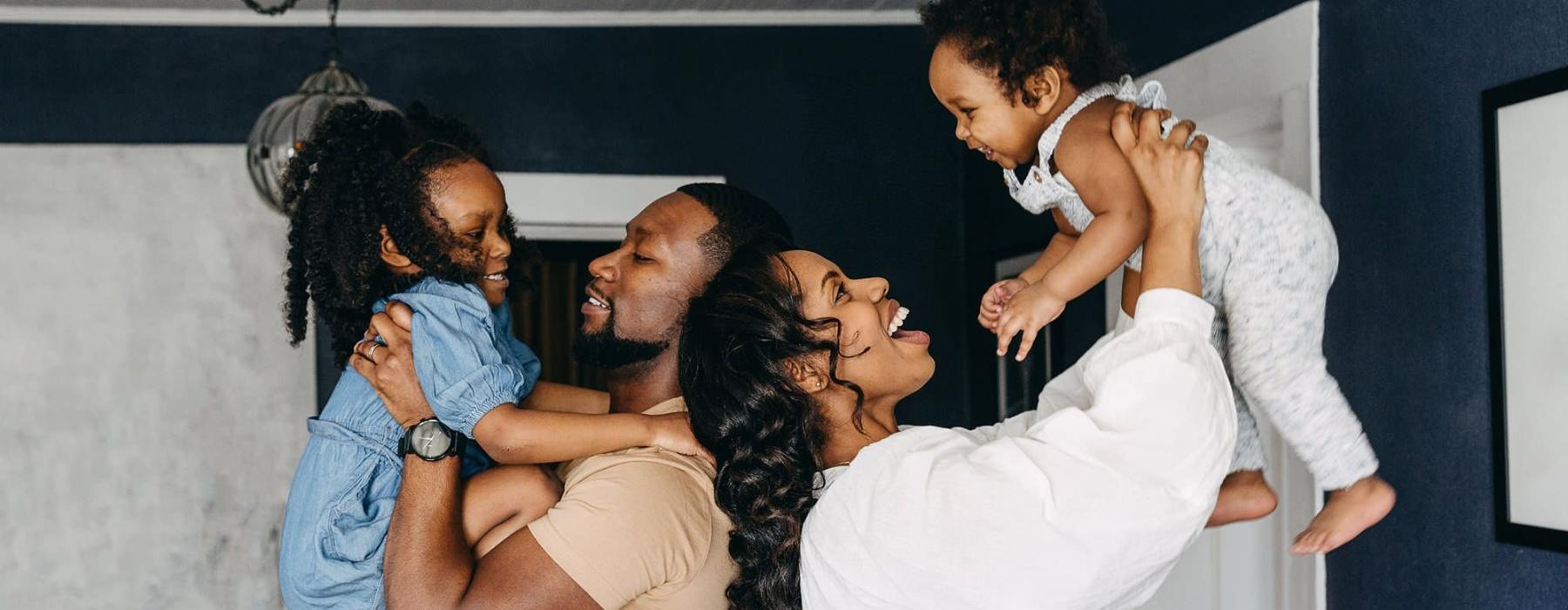 young parents hold up their children in room